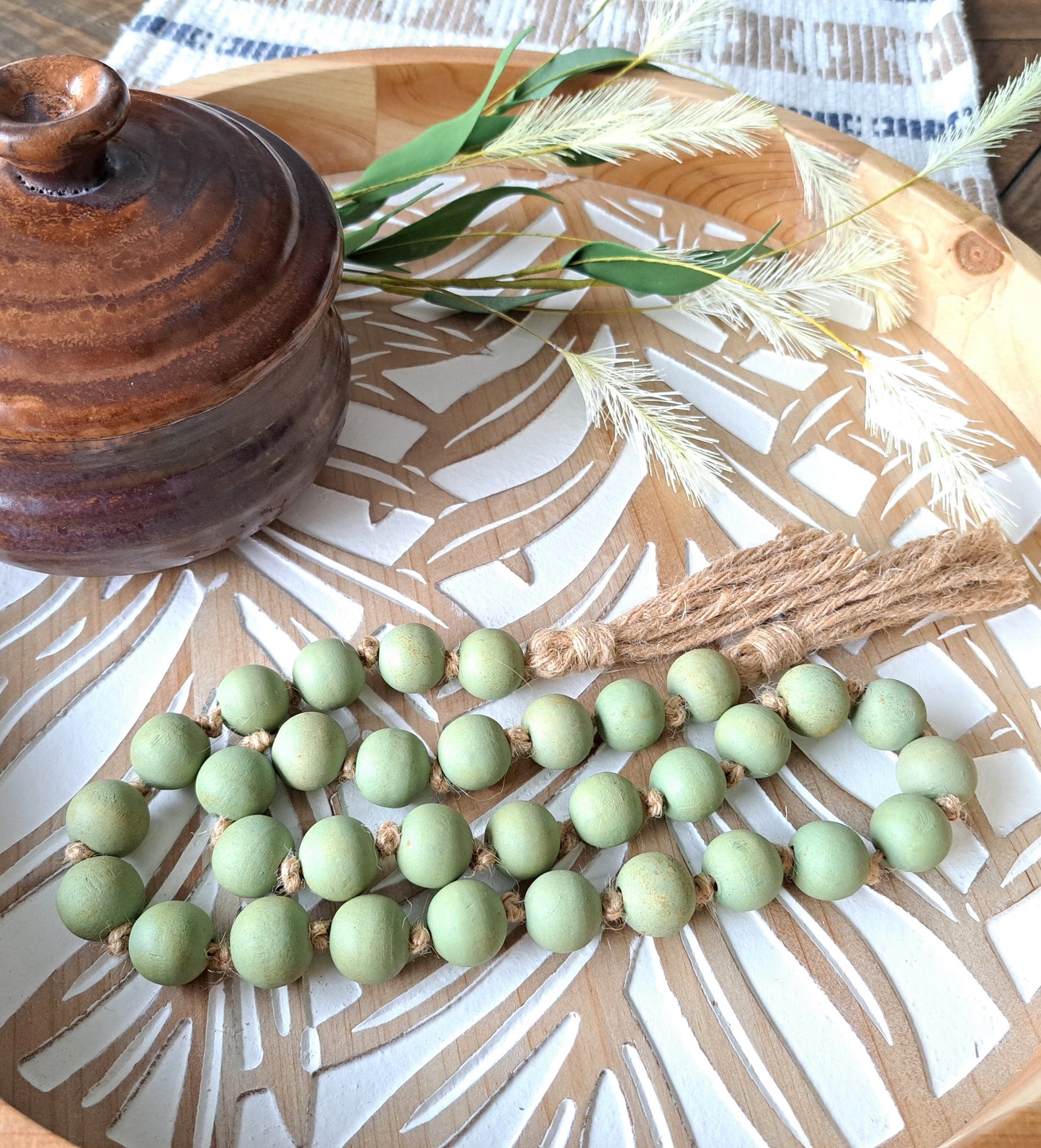 Weathered Landing's handmade sage green painted wooden bead garland with jute tassels. Made in Canada. Find garlands, plant hangers, pottery, art prints, and other home decor pieces at Weathered Landing. Located in Komoka with shipping to Canada and US.