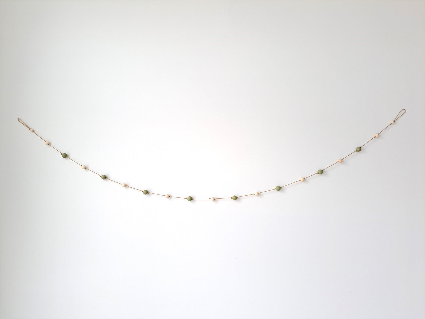 Weathered Landing's handmade sage green and natural wood bead garland. Beautiful in a nursery or on a fireplace mantel for a Scandi, boho, or modern farmhouse feel. Works great with neutral decor and is made with wood and jute. Find wooden bead garlands at Weathered Landing. Located in Komoka, Ontario. Shipping to Canada and US.
