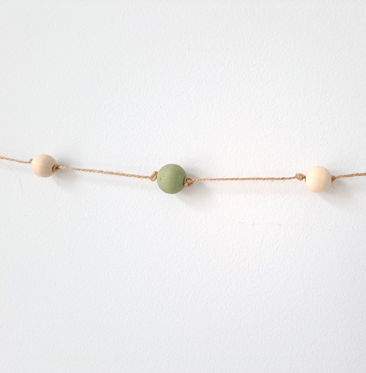 Weathered Landing's handmade sage green and natural wood bead garland. Beautiful in a nursery or on a fireplace mantel for a Scandi, boho, or modern farmhouse feel. Works great with neutral decor and is made with wood and jute. Find wooden bead garlands at Weathered Landing. Located in Komoka, Ontario. Shipping to Canada and US.