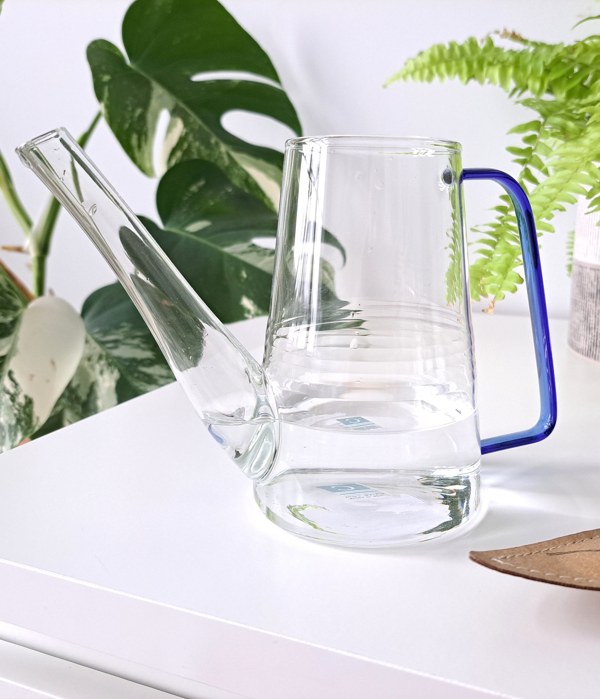 This extruded tube glass watering container is a perfect gift idea! Delicate and trendy, this water jug is great for getting into hard to reach spaces. Also makes a great vase for displaying fresh cut flowers. Comes with rustic metal snippers in the pouch.